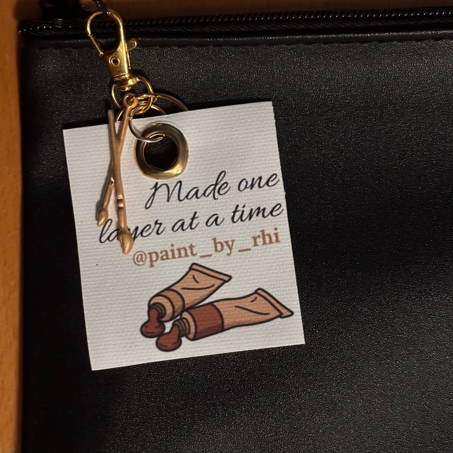 One Layer at a Time keychain clipped onto a bag